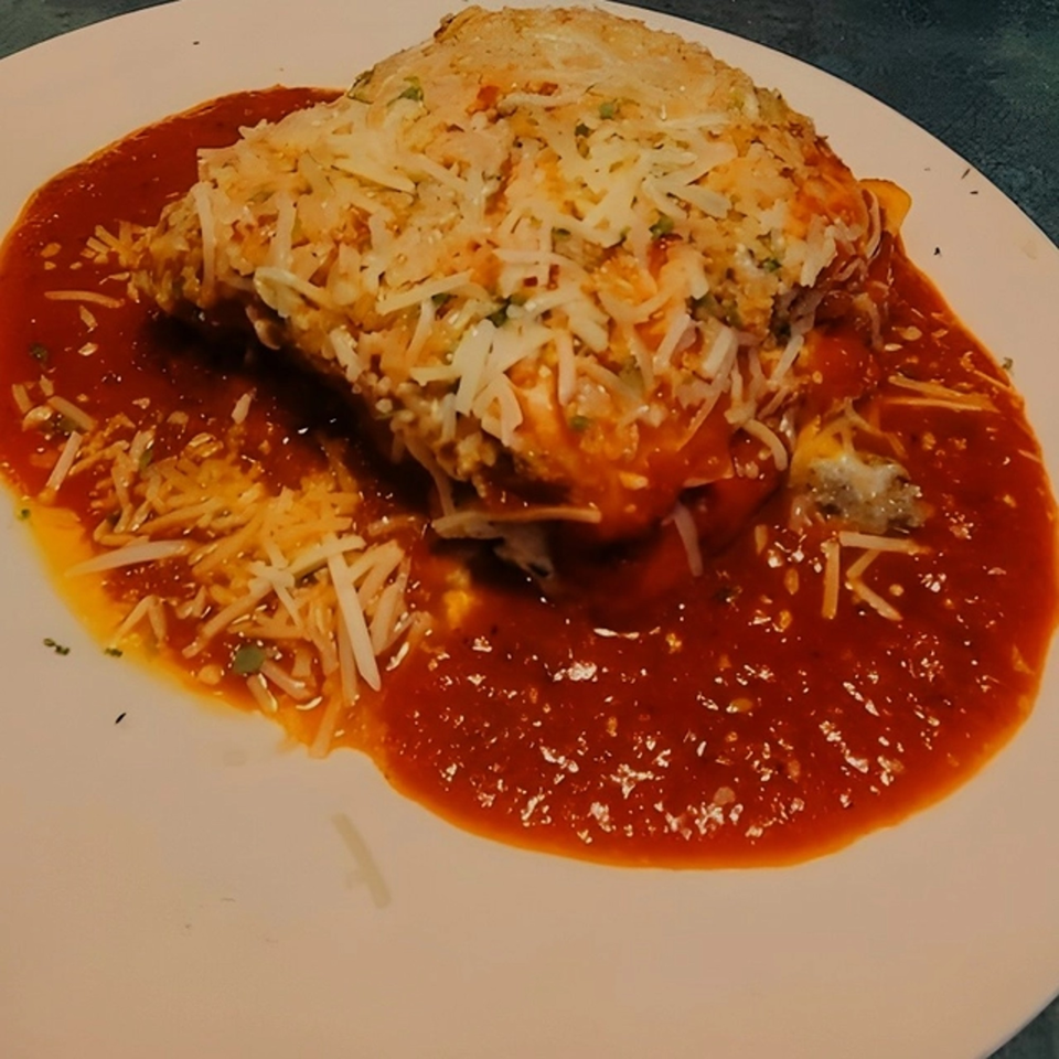 A large serving of Mama's Italian lasagna, topped with melted cheese and rich red sauce.
