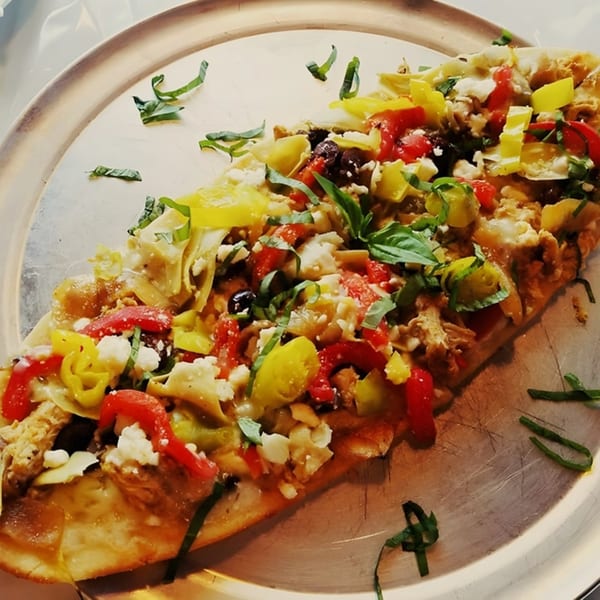 Mama's Italian Family Restaurant's flatbread pizza topped with colorful peppers, olives, cheese, and basil.